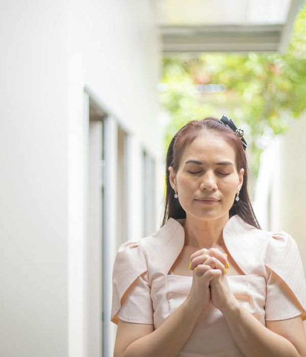 Person meditating peacefully outdoors with a serene background.